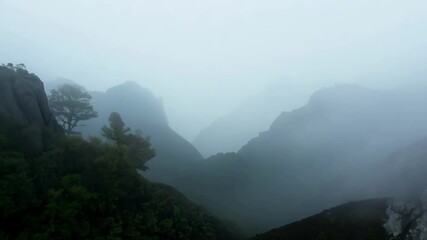 Wall Mural - fog is rolling over the tops of a mountain range, creating a mysterious and beautiful scene. the lus