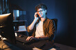 © Summit Art Creations - Young businessman calling on smartphone to customer or coworker, looking at computer screen of creative presentation surround work desk at neon modern office. Concept of new next project. Gusher.