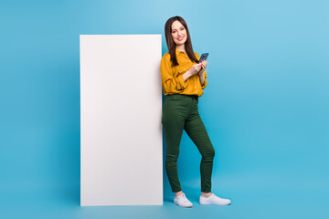 Wall Mural - Full length photo of pretty charming woman wear yellow shirt communicating device empty space isolated blue color background