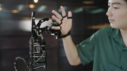 happy asian teenage boy student learning and testing electronic technology of hand and arm robot for