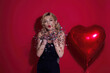 © Volodymyr - Beautiful young woman in black dress holding red heart baloons, valentines day. Romance date of sexy woman. Woman celebrating Valentines Day. Portrait pretty woman with red heart balloon.