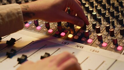Poster - Sound designer manipulating sound effects to enhance tunes on audio recordings, processing and mixing tracks to create a new song. Professional expert works in control room at studio. Camera A.