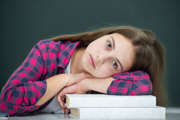 Upset sad School and students in classroom. Hard Education kids. Sleepy tired girl student in the school class. Studying and learning concept. Portrait of schoolgirl on the blackboard.