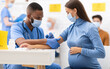 © Prostock-studio - African American Doctor Giving Coronavirus Vaccine Injection Shot To Pregnant Woman, Wearing Protective Face Mask In Clinic Hospital. Corona Virus Vaccination, Patient Getting Vaccinated For Covid-19