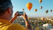 © LifeMedia - Close-up of a person taking a photo with a smartphone capturing vibrant hot air balloons in a clear blue sky, emphasizing travel and adventure.