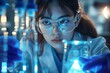 © k - Asian female scientist conducting chemical experiment in laboratory with blue light