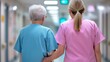 © PirisaTK - Elderly patient walking with nurse in hospital corridor wearing blue and pink uniforms  Concept of compassionate healthcare senior care patient centered service and positive aging experience