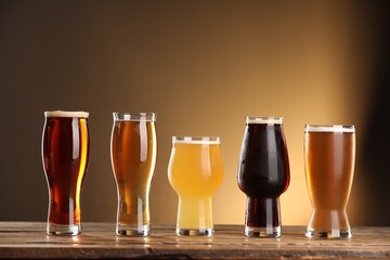 Sticker - Glasses with different types of beer on wooden table against color background