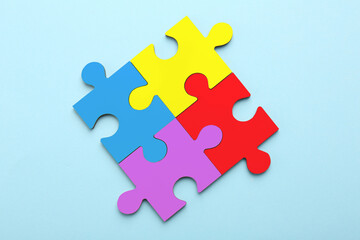 Sticker - Four colorful puzzle pieces on light blue background, top view. Symbol of autism