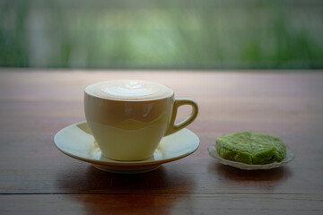 Side view of hot latte coffee with latte art in a white cup on wooden table