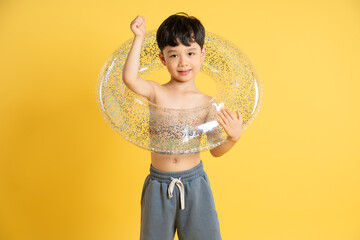 Image of an Asian boy wearing swimming goggles posing on a yellow background