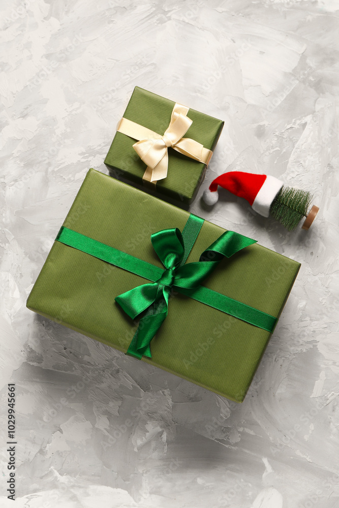 Green gift boxes and Christmas tree with Santa hat on grey background