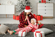 © Pixel-Shot - Happy mother and her little daughter in Santa hats at home on Christmas eve
