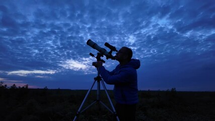Wall Mural - amateur astronomer looking at the cloudy evening skies, waiting for observing planets, stars, moon a