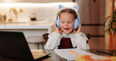 Sticker - Laptop, headphones and education with child in kitchen for online class, streaming and school. Elearning, knowledge and technology with girl in family home for academic tutor, growth and studying