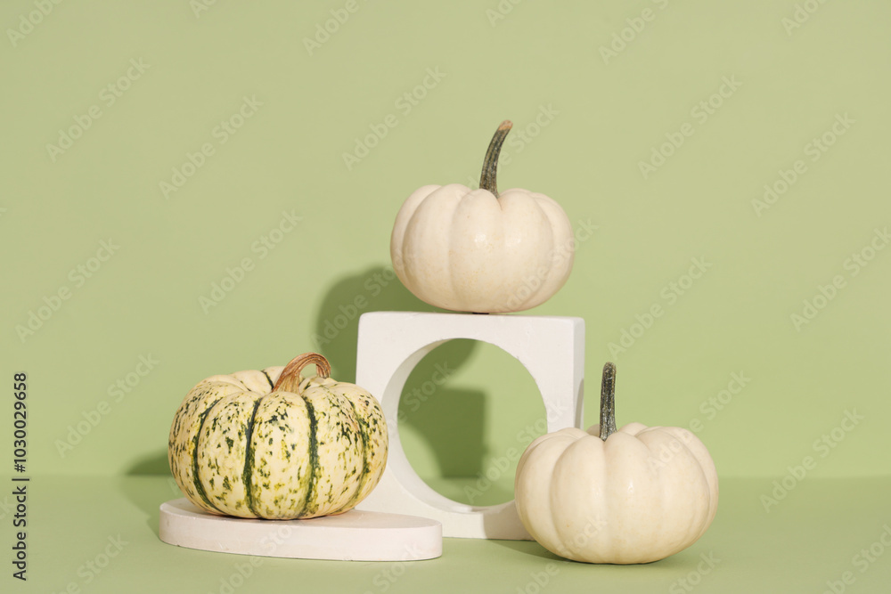 Decorative podiums with fresh pumpkins on green background