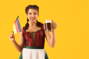 Wall Mural - Young Octoberfest waitress with beer and German flag on yellow background