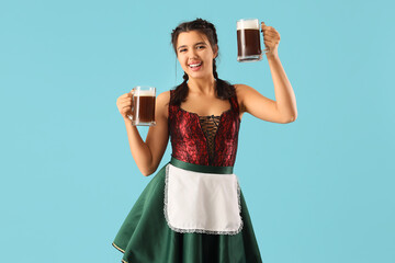 Wall Mural - Young Octoberfest waitress with beer on blue background