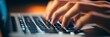 © Wannaeka - Close-up of person typing on laptop keyboard with metal keys on blurred desk background