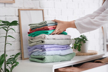 Sticker - Young woman putting stack of clothes into drawer at home, closeup