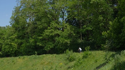 A man cyclist riding on a path in a green forest on a sunny summer day.