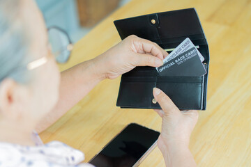 Back view of happy senior woman with credit cards and wallet paying bill for coffee and dessert