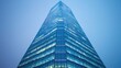 © Nitchalee N. - A modern skyscraper with a sleek, glass facade reaches upward against a soft, blue sky, creating an impressive and striking architectural presence.