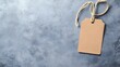 © PSCL RDL - Empty layout layout on grey background. Common blank label name tag hanging on neck with thread