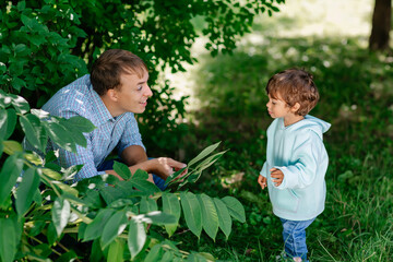 Wall Mural - Dad playing with his cute child in the park. Father and son having fun outdoors