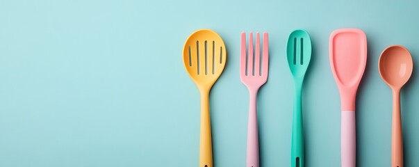 Colorful kitchen utensils lined up against a pastel blue background, perfect for modern cooking or culinary themes.