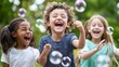 © ECLIVN - Three young children, a boy and two girls, laugh and play with bubbles outdoors on a bright day.