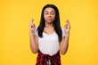 © InsideCreativeHouse - Hopeful happy young African American girl woman female student crossing fingers hoping for good luck, making wish asking dream come true isolated on yellow studio background, superstition beliefs