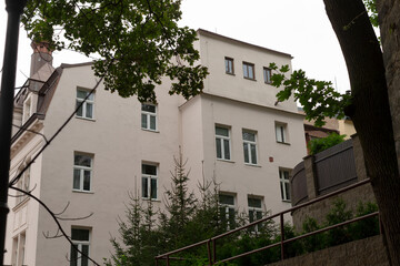 A beautiful white building features elegant stairs that lead up to its inviting entrance, surrounded by greenery and a clear blue sky