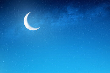 A crescent moon is shining brightly in the night sky. The stars are scattered throughout the sky