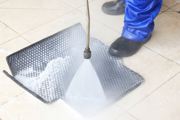 Poster - Man washing rubber car mat with high pressure water jet indoors, closeup