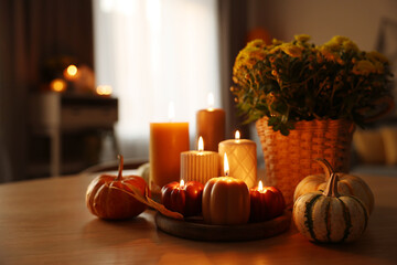 Poster - Burning candles, pumpkins and flowers on wooden table indoors. Space for text