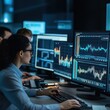 © Jang - Team of financial analysts reviewing charts and graphs on multiple computer screens.