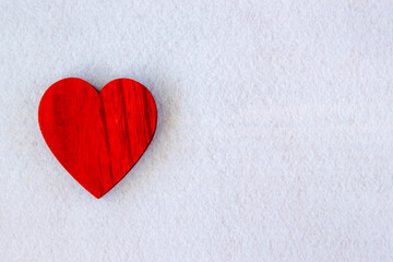 red wood heart on the white fabric background.