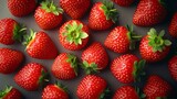 Una vista de arriba de fresas frescas dispuestas en un fondo oscuro, resaltando su color rojo vibrante y hojas verdes.