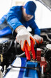 © zphoto83 - A mechanic working on a car battery using jumper cables in an auto repair shop on a busy afternoon