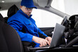 © zphoto83 - Mechanic in blue uniform working on laptop inside car to diagnose technical issues at an auto repair shop during daytime