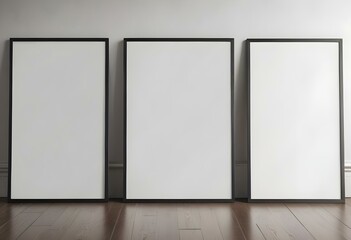 Three empty picture frames on a wooden floor against a white wall.