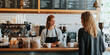 © MNStudio - Cheerful barista serving customer a cup of coffee at coffee shop. Happy cafe employee standing by a counter waiting for payment. Helping client at checkout.