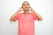 © Stora Space - An Indonesian, Asian man wearing a pink tshirt having a headache, chest pain and stomach ache with hands holding head, chest and stomach. isolated in white background