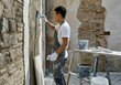© Alexandra - Construction worker is plastering an external brick wall using a trowel, during a home renovation project