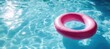 © Grigor - Pink inflatable ring floating in a swimming pool.