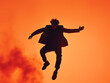 © Aisyaqilumar - An happy men jumping on an orange background. In a silhouette street fashion outfit.