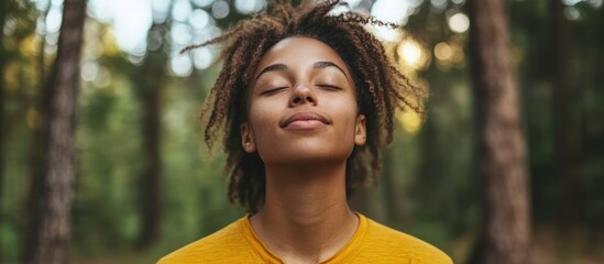 Wall Mural - Young woman with dreadlocks meditating in the forest with her eyes closed.