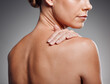 © KayExam/peopleimages.com - Body, skincare and model with self care, dermatology and beauty on gray studio background. Woman, shoulder touch and wellness with healthy, glow and skin with cosmetics results or antiaging treatment