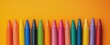 © ibnu - Colorful crayons forming a line on an orange background